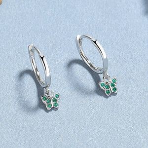 A collection of hoop earrings with butterfly charms attached, displayed against a blue background.