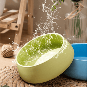 Green and blue ceramic bowls with water splashing out on a textured surface.