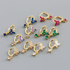 Gold earrings with colorful gemstones on a gray background