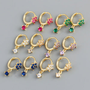 Gold hoop earrings with colorful gemstones on a gray background