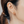 Close-up of an ear wearing a gold earring with a colorful gemstone.