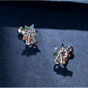 Ferris wheel-shaped earrings with colorful gemstones on a blue surface