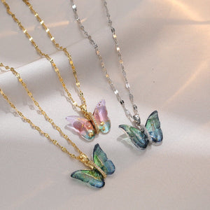 Butterfly-shaped pendants on gold and silver chains against a light background
