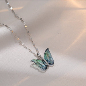 A collection of butterfly pendant necklaces with gold and silver chains and multicolored gemstone butterflies.