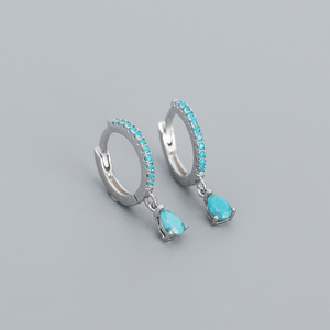 Silver hoop earrings with turquoise stones on a gray background