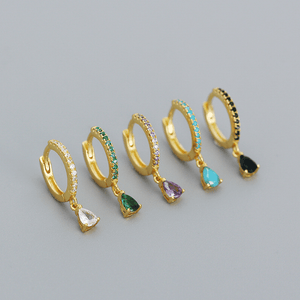 Set of gold hoop earrings with colorful gemstones on a gray background
