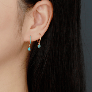 Close-up of a person wearing turquoise earrings with a blurred background