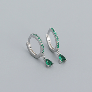 Silver hoop earrings with green gemstones on a gray background