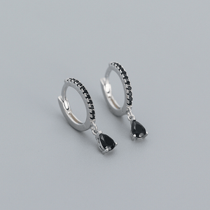 Silver hoop earrings with black teardrop gemstones on a gray background