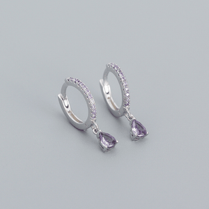 Silver hoop earrings with purple teardrop gemstones on a gray background