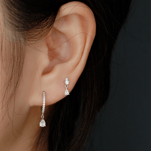 Close-up of a person wearing diamond earrings with a dark background