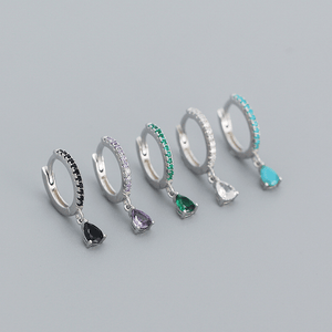 Set of silver hoop earrings with gemstone drops on a gray background