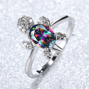 Silver ring with a colorful gemstone on a glittery background