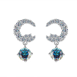 A pair of silver drop stud earrings with central moissanite gemstone surrounded by smaller clear crystals on a white background.