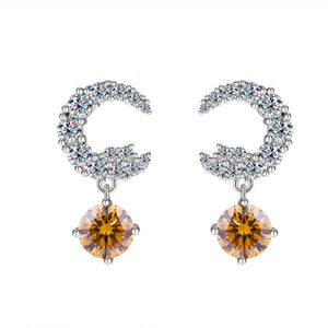 A pair of silver drop stud earrings with central moissanite gemstone surrounded by smaller clear crystals on a white background.