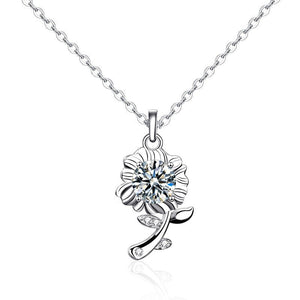 A sterling silver necklace with a sunflower charm featuring a green moissanite gemstone in the center, surrounded by small white accent stones, displayed against a blue background.