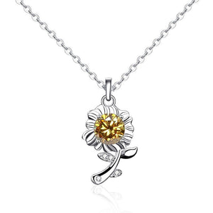 A sterling silver necklace with a sunflower charm featuring a green moissanite gemstone in the center, surrounded by small white accent stones, displayed against a blue background.