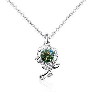 A sterling silver necklace with a sunflower charm featuring a green moissanite gemstone in the center, surrounded by small white accent stones, displayed against a blue background.