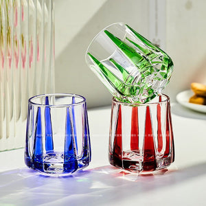 Three colorful glass tumblers on a light surface with a blurred background