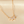 Delicate gold necklace with leaf-shaped pendants on a beige background