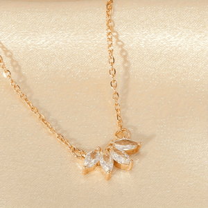 Delicate gold necklace with leaf-shaped pendants on a beige background