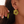 Close-up of a person wearing green earrings with gold loops.