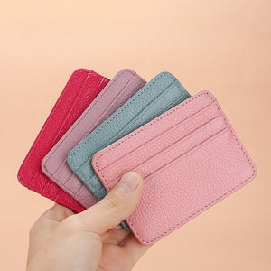 Set of pink, purple, and blue card holders held by a hand on a beige background