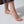 Gold anklet on a foot against a neutral background