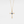 Gold cross necklace with a blue gemstone on a light gray background