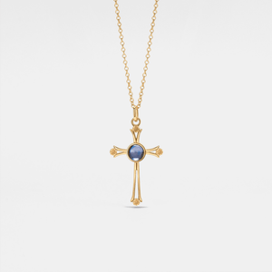 Gold cross necklace with a blue gemstone on a light gray background
