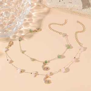 Delicate necklace with moon and star charms on a beige surface