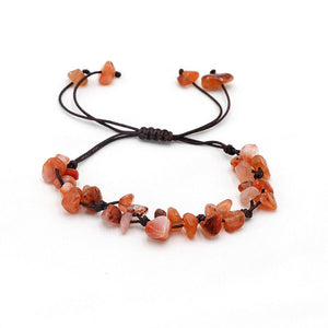 A collection of braided bracelets with various colored crystal stones, displayed on a white surface.