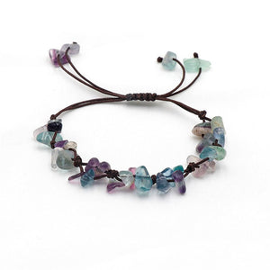 A collection of braided bracelets with various colored crystal stones, displayed on a white surface.