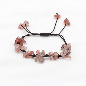 A collection of braided bracelets with various colored crystal stones, displayed on a white surface.