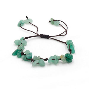 A collection of braided bracelets with various colored crystal stones, displayed on a white surface.