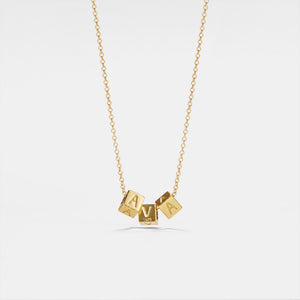 A gold-plated square letter bead name necklace on a chain, with the beads arranged to spell out a name.