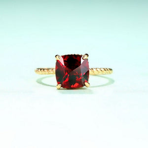 Gold ring with a red gemstone on a light blue background