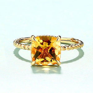 A cushion cut topaz ring with gold plating on a silver band, displayed against a light background.