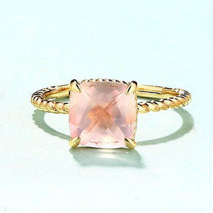 Gold ring with a pink gemstone on a light blue background