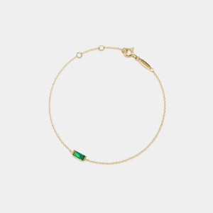 Gold bracelet with a green gemstone on a white background