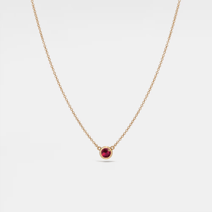 Gold necklace with a red gemstone on a white background