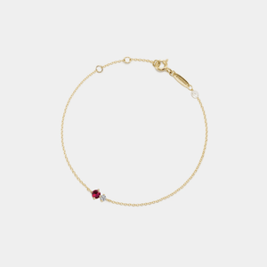 Gold bracelet with a red gemstone on a white background