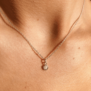 Necklace with a small pendant on a person's neck