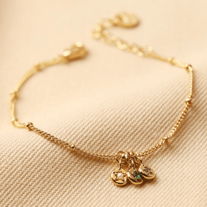 Gold bracelet with charms on a beige fabric background