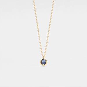 Gold necklace with a blue gemstone pendant on a light gray background