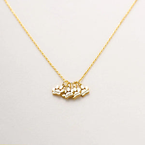 Gold necklace with heart-shaped charms on a light gray background
