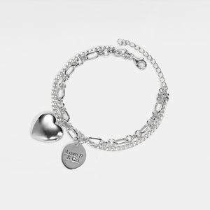 Silver bracelet with heart locket and 'Love P & Co' tag on a white background