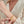 Woman wearing a gold bracelet with heart locket and 'Love P & Co' tag on a white background