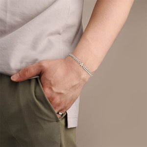 Person wearing a silver bracelet on a neutral background