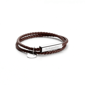 Brown braided leather bracelet with a silver tag on a white background